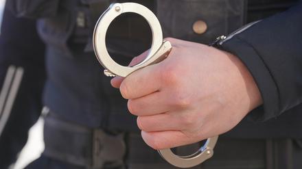 Ein Polizist hält Handschellen in der Hand. (Symbolfoto)