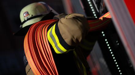 Eine Einsatzkraft der Feuerwehr nimmt einen Schlauch aus einem Einsatzfahrzeug der Feuerwehr.