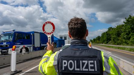Ein Bundespolizist hält auf der A64 mit einer Kelle ein Fahrzeug an. 
