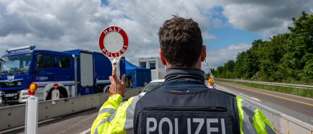 Ein Bundespolizist hält auf der A64 mit einer Kelle ein Fahrzeug an. 