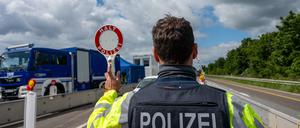 Ein Bundespolizist hält auf der A64 mit einer Kelle ein Fahrzeug an.
