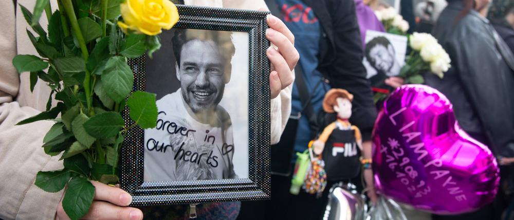 Fans trauern in Köln um Liam Payne und zeigen ein Foto des Sängers, der am Mittwoch vom Balkon seines im dritten Stock gelegenen Hotelzimmers in der argentinischen Hauptstadt Buenos Aires stürzte und starb.