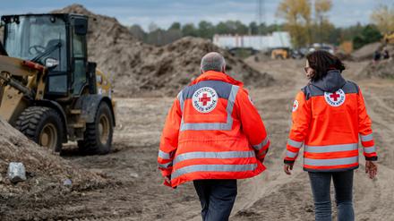 Mitarbeiter des Deutschen Roten Kreuzes laufen vor der Grundsteinlegung für den Neubau eines Bevölkerungsschutzzentrums des Deutschen Roten Kreuzes über das Gelände.