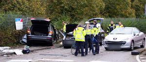 Einsatzkräfte der Polizei stehen an der Unfallstelle neben drei Fahrzeugen. Bei dem schweren Verkehrsunfall sind nach Polizeiangaben drei Personen gestorben.
