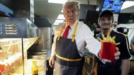 Donald Trump (l), Präsidentschaftskandidat der Republikaner und ehemaliger US-Präsident, gibt eine Pommes-Bestellung aus.