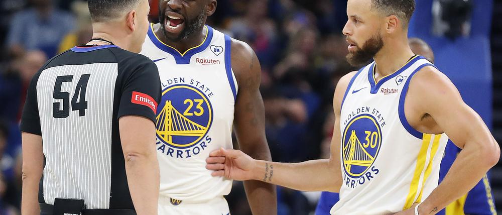 Ray Acosta (l.) und Stephen Curry von den Golden State Warriors diskutieren mit einem Schiedsrichter.