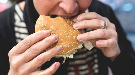 In einer McDonalds Filiale in Frankfurt beißt ein Mensch in einen Hamburger.