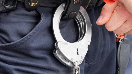 Handfesseln aus Metall hängen am Gürtel eines Polizisten. 