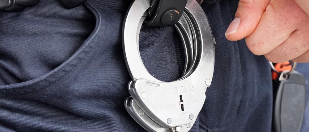Handfesseln aus Metall hängen am Gürtel eines Polizisten. 