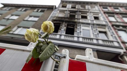 Eine weiße Rose an einer Absperrbake vor einem im März abgebrannten Mehrfamilienhaus in Solingen.