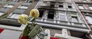 Eine weiße Rose an einer Absperrbake vor einem im März abgebrannten Mehrfamilienhaus in Solingen.