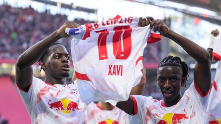 Leipzigs Castello Lukeba (l) und Amadou Haidara halten nach dem 2:1 ein Trikot des verletzten Xavi Simons nach oben.