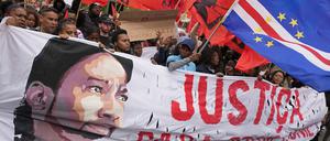 Auf einer Demo gegen Rassismus und Polizeigewalt in Lissabon hält ein Mann eine kapverdische Flagge, während andere ein Transparent mit einem Bild von Odair Moniz, einem Schwarzen kapverdischer Herkunft tragen, der am Montag von der Polizei erschossen wurde.