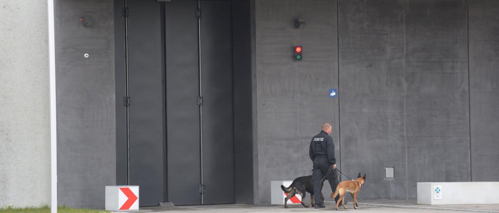 Ein Justizangehöriger geht mit zwei Hunden vor der Justizvollzugsanstalt Augsburg-Gablingen: Hier solle es mutmaßlich zu Gefangenenmisshandlung gekommen sein.