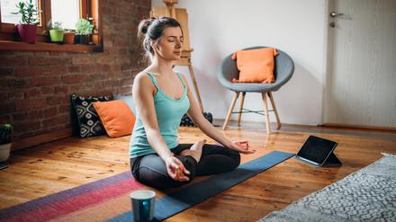 Junge Frau entspannt durch ihre Meditationspraxis zu Hause.