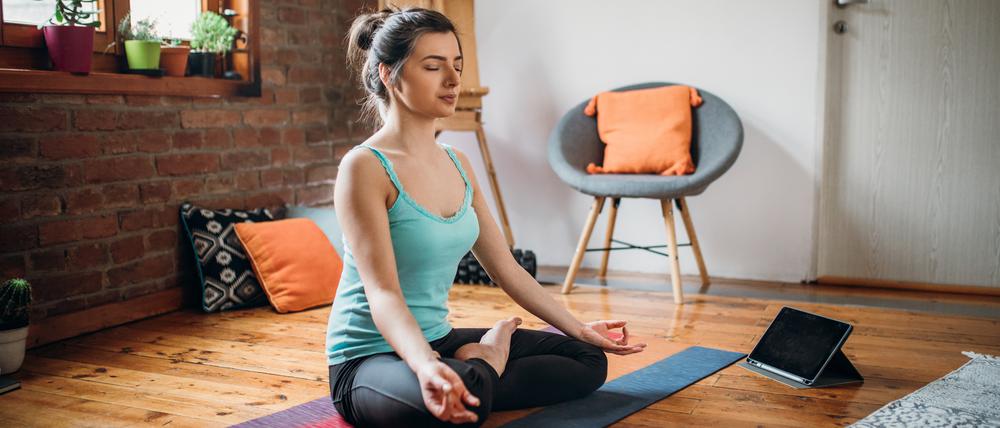 Junge Frau entspannt durch ihre Meditationspraxis zu Hause.