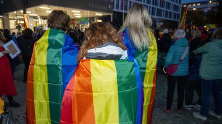 Demonstrierende in Neubrandenburg haben sich Regenbogenfahnen über die Schultern gelegt.  