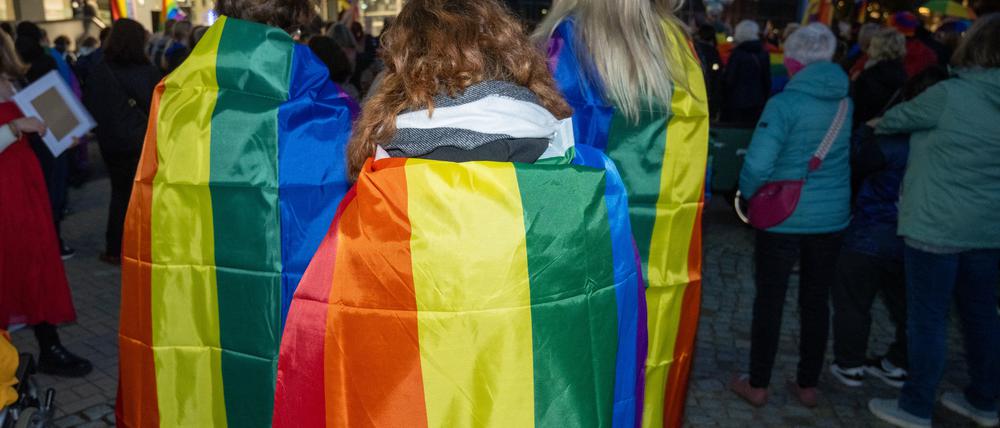 Demonstrierende in Neubrandenburg haben sich Regenbogenfahnen über die Schultern gelegt.  