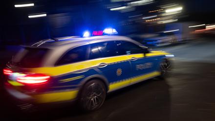 Ein Polizeifahrzeug fährt mit Blaulicht an einem Gebäude vorbei (Symbolbild)