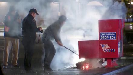 Einsatzkräfte ziehen den brennenden Inhalt aus einem Wahlbriefkasten, nachdem dieser bei einem mutmaßlichen Brandanschlag in Vancouver, Washington in Brand gesetzt wurde.