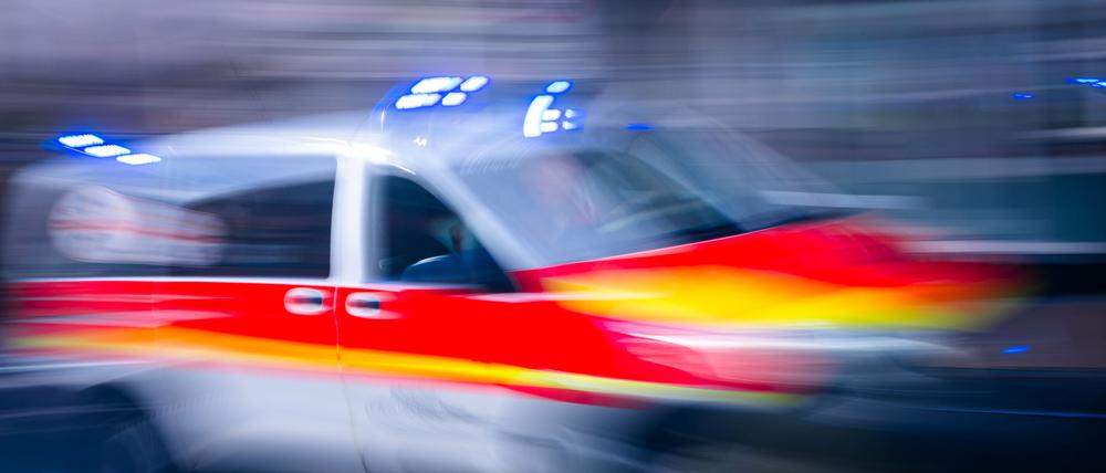 Ein Rettungsfahrzeug ist mit Blaulicht auf einer Straße unterwegs.