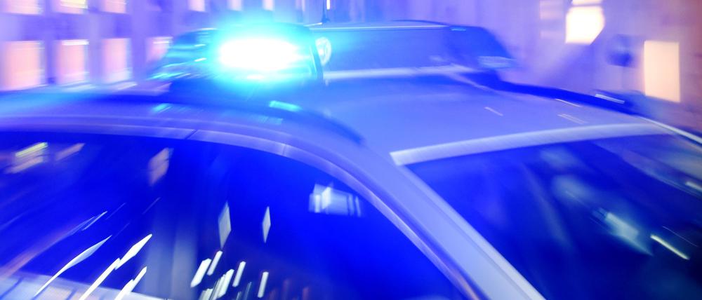 Ein Streifenwagen der Polizei steht mit eingeschaltetem Blaulicht auf der Straße.