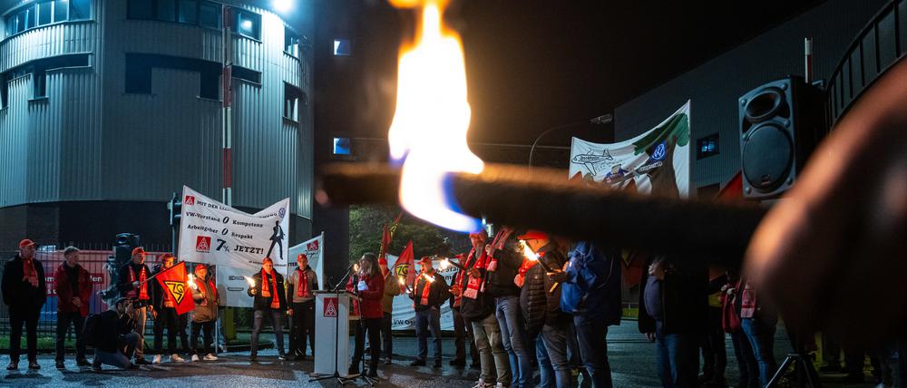 Mitarbeiter von Volkswagen stehen mit Fackeln vor dem VW-Werk in Osnabrück.