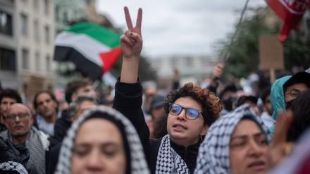 Eine junge Aktivistin auf einer propalästinensischen Demonstration streckt ihren Arm in die Höhe, die Hand zu einem Victory-Zeichen geformt.