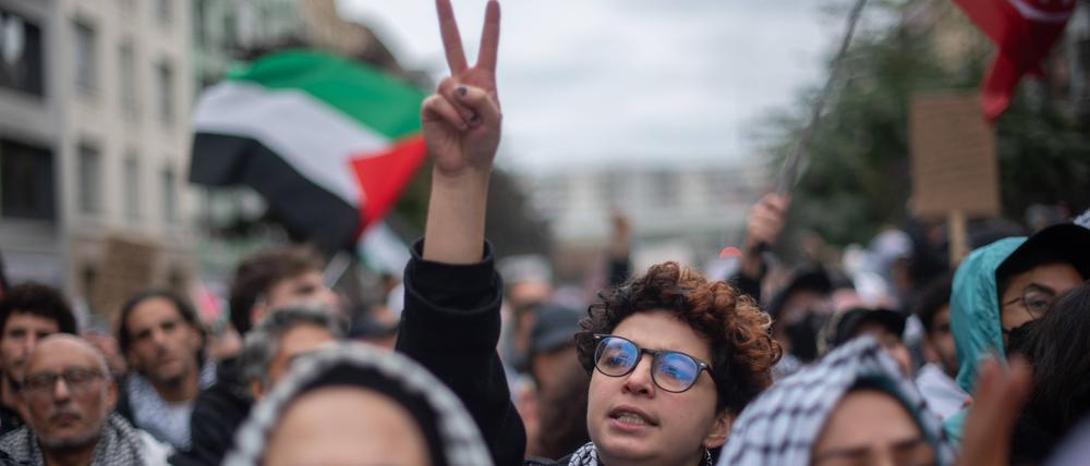 Eine junge Aktivistin auf einer propalästinensischen Demonstration streckt ihren Arm in die Höhe, die Hand zu einem Victory-Zeichen geformt.