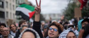 Eine junge Aktivistin auf einer propalästinensischen Demonstration streckt ihren Arm in die Höhe, die Hand zu einem Victory-Zeichen geformt.