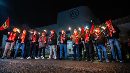 Mitarbeiter von Volkswagen stehen mit Fackeln vor dem Werk in Osnabrück. 