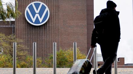 Ein Mann zieht einen Reisekoffer vor dem Volkswagen-Firmengelände.