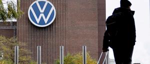Ein Mann zieht einen Reisekoffer vor dem Volkswagen-Firmengelände.