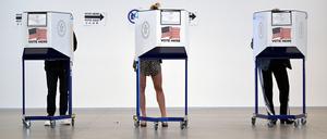Drei Wähler hinter Wahlkabinen in einem Wahllokal in New York City.