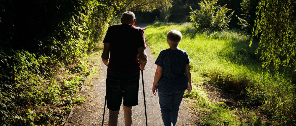 Ein altes Ehepaar läuft bei einem Spaziergang gemeinsam einen Weg entlang. (Symbolfoto)
