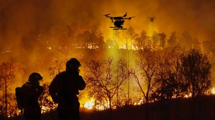 Löschdrohnen sprühen brandhemmende Chemikalien in einen Waldbrand. Drohnen werden bei Löscharbeiten immer wichtiger. 