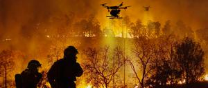 Löschdrohnen sprühen brandhemmende Chemikalien in einen Waldbrand. Drohnen werden bei Löscharbeiten immer wichtiger. 