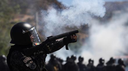 Ein Polizist in Bolivien feuert Tränengas auf Demonatranten.