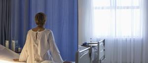 Eine Patientin sitzt auf einem Krankenhausbett und schaut aus dem Fenster.