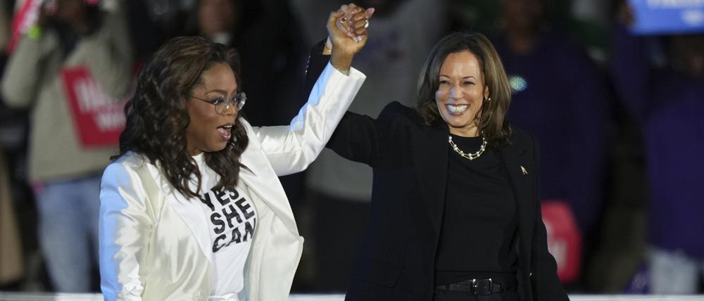 Oprah Winfrey (links) hält einen Arm von Kamala Harris hoch, wie bei einer Siegerverkündung.