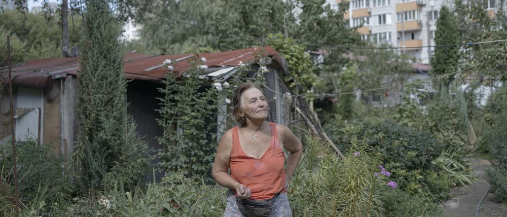 Eine Frau in ihrem Schrebergarten in der Ukraine, vor Wohnblocks. 