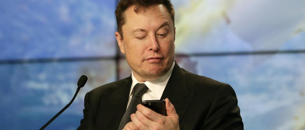 Elon Musk, Konzernchef des US-Elektroautoherstellers Tesla, schaut während einer Pressekonferenz nach dem Test einer Falcon 9 Rakete des Unternehmens auf ein Handy.  