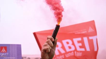 Ein Mann zündet während des Warnstreiks der IG Metall eine rote Fackel an.