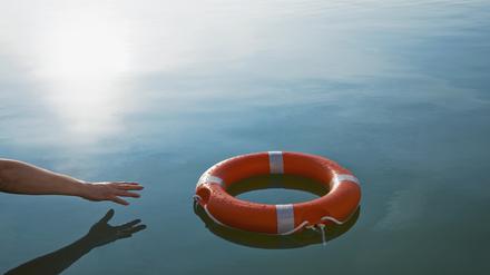 Eine Hand greift nach einem Rettungsring. Was können wir tun, um inmitten Weltlage und der emotionalen Flut einen klaren Kopf zu behalten?