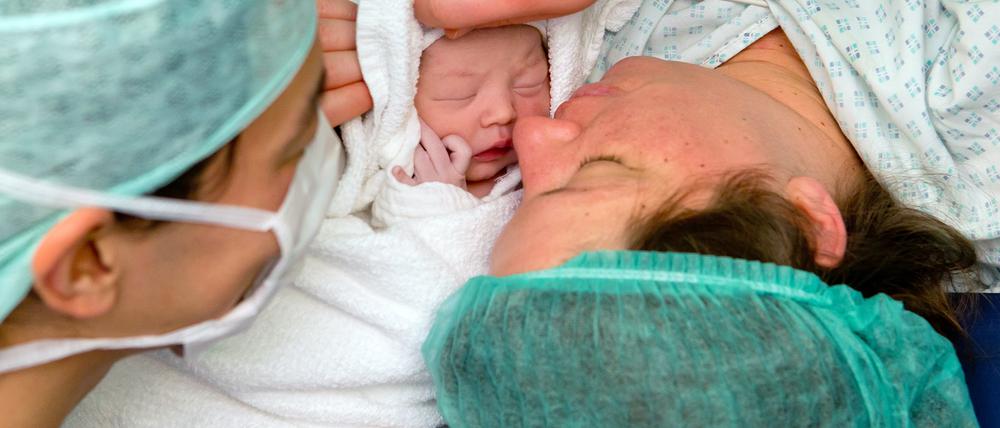 ARCHIV - Die kleine Helena Elisa liegt am 12.12.2012 im Kreißsaal der Frauenklinik in Erlangen (Bayern) bei ihren Eltern Hanna und Bo. Das Baby kam per Kaiserschnitt um 12 Uhr 12 zur Welt. Foto: Daniel Karmann/dpa (zu dpa „Immer mehr Kinder werden bei der Anfahrt zur Geburtshilfe geboren“ vom 27.11.2016) +++(c) dpa - Bildfunk+++ | Verwendung weltweit