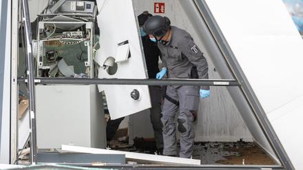 Zwei Polizisten vom Kampfmittelräumdienst stehen in einer Bankfiliale, in der ein Geldautomat gesprengt wurde. 