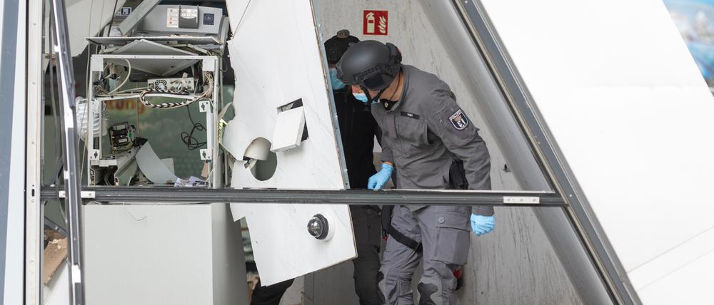 Zwei Polizisten vom Kampfmittelräumdienst stehen in einer Bankfiliale, in der ein Geldautomat gesprengt wurde.