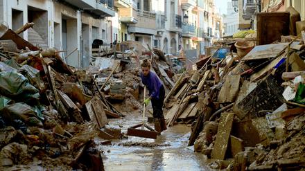 Eine Frau in Paiporta bei Valencia versucht, Schlamm aus der überfluteten Straße zu entfernen.  