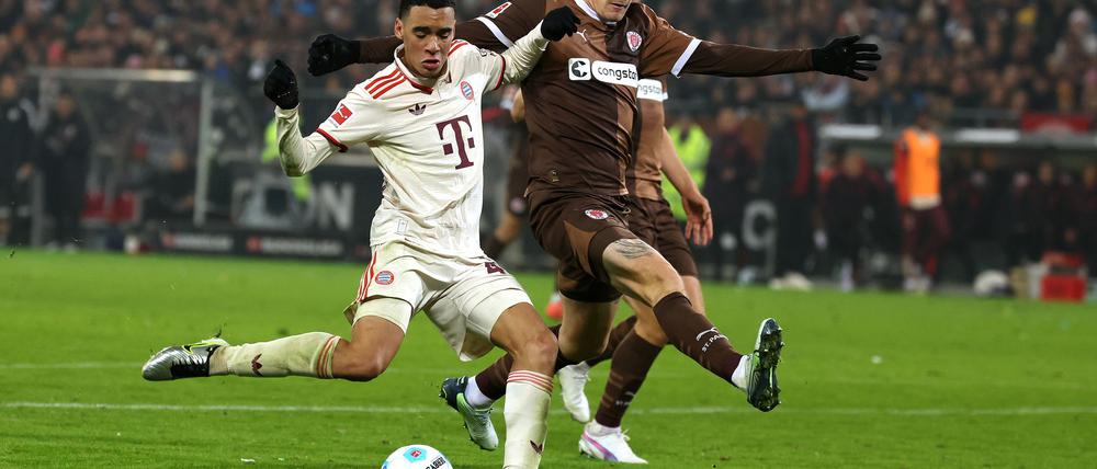 FC St. Paulis Abwehrspieler Eric Smith (r) verletzt sich beim Spiel gegen den FC Bayern.  