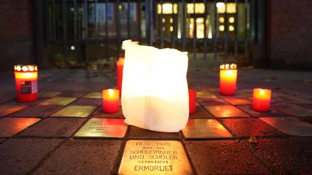 Kerzen stehen an Stolpersteinen.